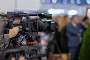 A camera lens captures the essence of a press conference, highlighting media coverage and...