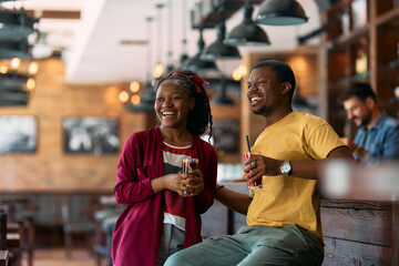 Cheerful black couple enjoying while having drink in  cafe.