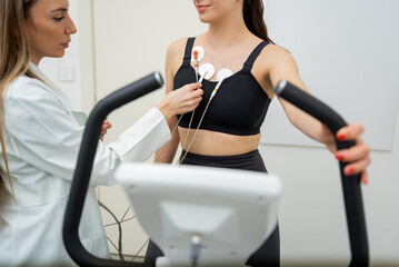 Young woman undergoing a fitness evaluation with professional assistance in a modern gym