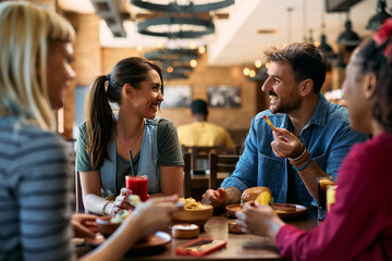Young happy couple communicating while eating in  pub.