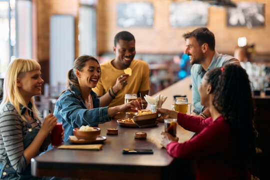 Group of happy friends having  snack while drinking in  bar.