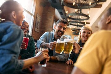 Cheerful group of friends toasting while gathering in pub.