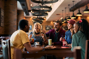Group of happy friends laughing while gathering in pub.