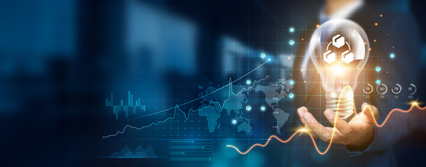 Businessman holding creative light bulb with growth graph and supply chain icons. Revamping...