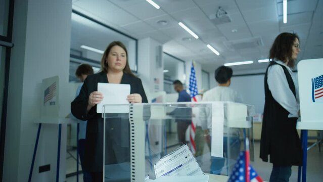 Diverse voters, American people vote for future president in voting booths at polling station. Caucasian woman puts ballot in box. National Election Day in the United States of America. Slow motion.