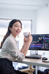 Investor businesswoman drinking coffee to taking break and relaxation with happiness after working on computer about stock and marketing of new startup to analysis trade and investment of project - 788991010