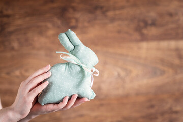 Easter bunny in female hands on a light background.