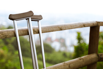 Crutches supported on wood with natural background. Woman using crutches due to fracture....