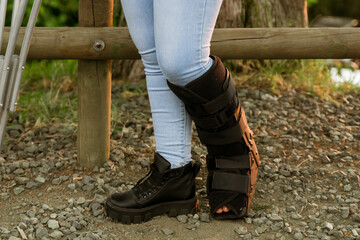 Young woman wearing splint for fractured fibula. Disability, free air and crutches.