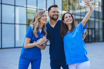 Healthcare workers selfie at work. Multiracial doctors and nurses taking picture using smartphone. Close up of Diverse medicine students in uniform taking selfie in front of Hospital - 789005868