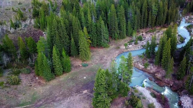 Aerial: Drone Panning Shot Of Bridge Over River Flowing In Stream At Tranquil Forest - Flathead National Forest, Montana