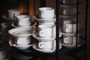 Coffee mugs stacked background. Ceramic mugs on black shelf. Coffee time background. Simple tea cups. Pile of mugs. Restaurant coffee table. Group of cups. Catering company.