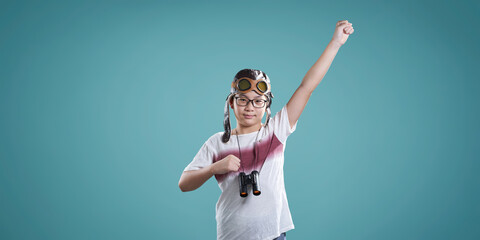 Young boy pretending to fly with aviator goggles and binoculars