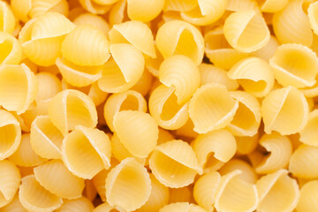 Uncooked, yellow, small shell shaped pasta background. Top view. Close-up