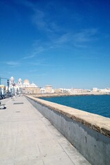 Cadiz embankment panorama with cathedral the Santa Cruz, big breakwater stones and Atlantic ocean....