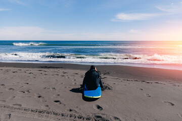 Back view man surfer with blue surfboard in wetsuit surfing in ocean on spot Kamchatka Russia,...