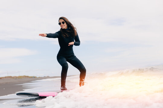 Action photo surfer happy woman in wetsuit with surfboard on winter surfing in ocean. Concept adventure Extreme sport