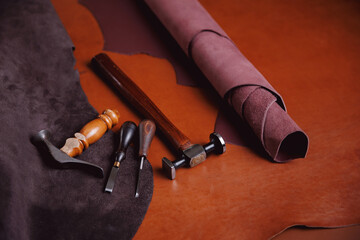 Natural leather brown color dark background with tools of shoes maker, copy space