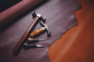 Equipment of Tailor for making shoe on background different rolls natural brown leather. Banner shoemaker industry, craftsman of workshop for skin