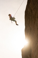 A man is jumping off a cliff with a rope. Concept of adventure and excitement, as the man is taking...