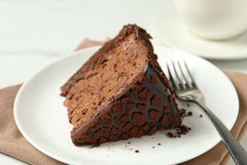 Piece of delicious chocolate truffle cake and fork on table, closeup