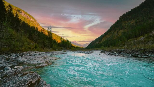 Mountain river in Austria alps with vibrant autumn evening sky. Cinemagraph loop. Water rushing along colorful trees.