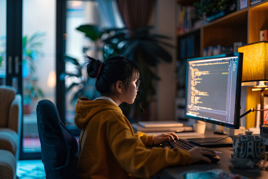 girl coding on computer in a dimly lit room
