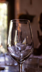 Close-up of glass wine glass illuminated by evening light reflecting a window overlooking a forest of a rustic restaurant of a mountain hotel for a romantic date.