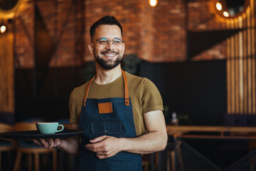 Happy confident young waiter entrepreneur looking at camera, smiling male small cafe business owner employee standing in restaurant, millennial businessman wear apron posing in coffee shop - 789036608