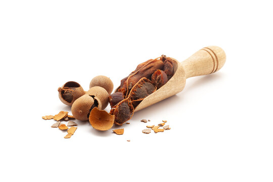 Front view of a wooden scoop filled with Fresh Organic Sweet Tamarind (Tamarindus indica) Frruit. Isolated on a white background.