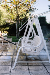 Young girl hand cleaning garden rocking chair with pressurized water machine in summer. Summer...