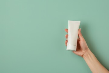 Hand Holding Blank Cosmetic Tube on Pastel Green Background