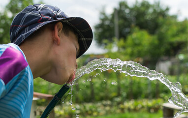 Image of a little boy on the background of a water fountain - obrazy, fototapety, plakaty
