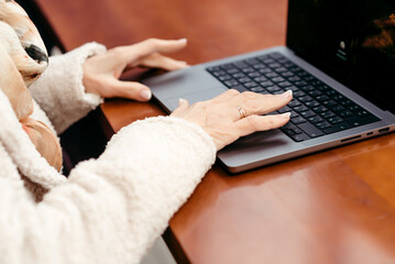 Hands of an elderly woman over a laptop keyboard