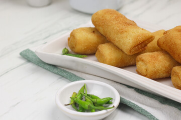 Risoles, one of Indonesian popular snack. Made from crepe skin filled with vegetables, chicken, coated with bread crumbs and deep fry. White marble background.   