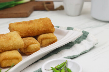 Risoles, one of Indonesian popular snack. Made from crepe skin filled with vegetables, chicken, coated with bread crumbs and deep fry. White marble background.   