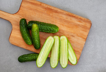 pickling cucumbers, cut on wooden chopping board on mottled grey