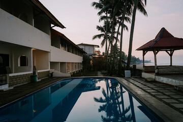 Tranquil coastal living awaits in this villa with a pool and coconut trees, an epitome of tropical paradise.