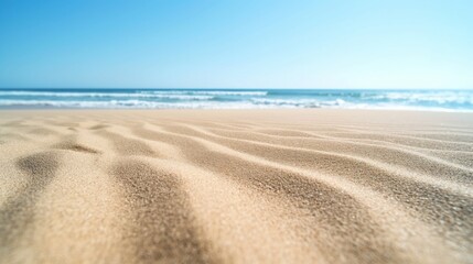 The beach background with smooth fine sand that is softly colored, turquoise waves lap a soft sand beach beneath a bright blue sky.