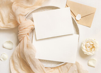 Horizontal Cards near cream fabric knot and flowers on plates top view copy space, wedding mockup