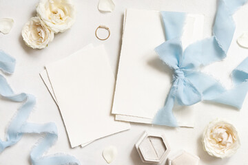 Cards tied with a light blue ribbons on white table top view, copy space, wedding stationery mockup - obrazy, fototapety, plakaty