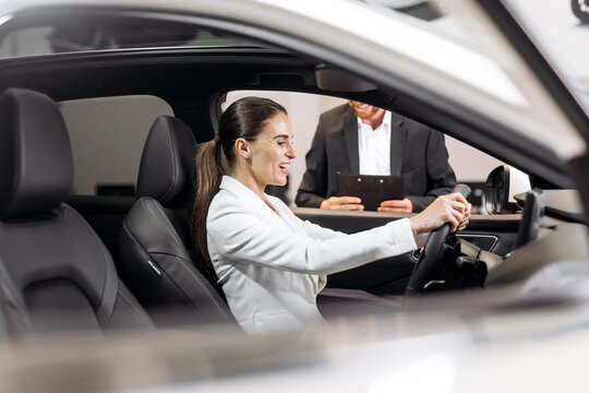 An interested buyer consults with a car dealership manager about the models and characteristics of a modern electric car. Concept of buying and selling a car, deal.