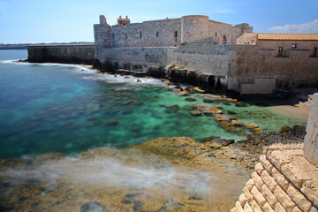 The fortifications of Castello Maniace (Maniace Castle) in Ortigia Island, Syracuse, Sicily, Italy, with clear and colorful water - obrazy, fototapety, plakaty