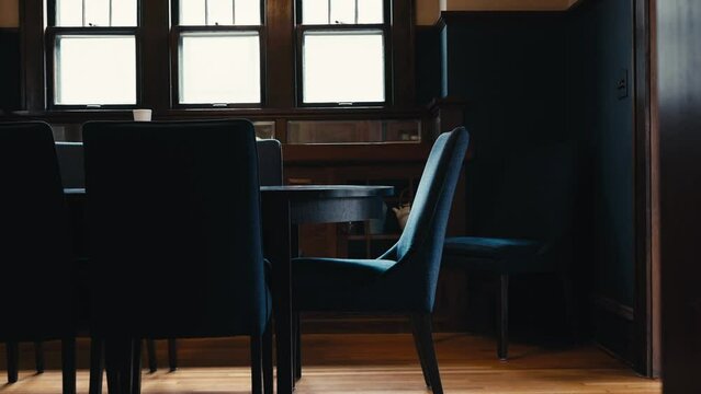 a navy chair sitting around a dining table inside of a home with wooden floors