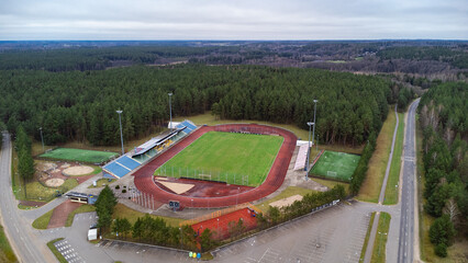 aerial view from drone of a football stadium with a football field located in a pine forest