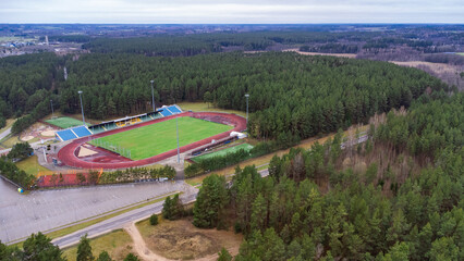 aerial view from drone of a football stadium with a football field located in a pine forest