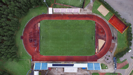 Soccer city stadium located in a pine forest, drone top view