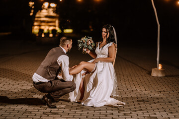 Valmiera, Latvia- July 28, 2023 - Groom kneeling in front of the bride lifting her dress, outdoor...