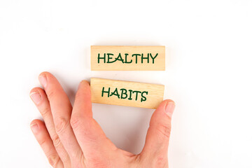 Business and Healthy habits concept. Concept word Healthy habits on wooden blocks made up by human hand on a white background