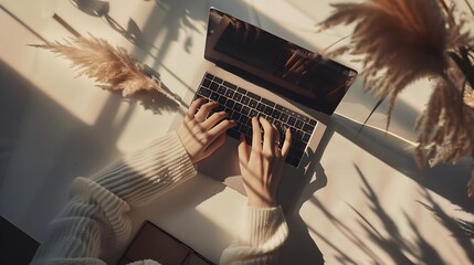 Flatlay of person hands working on laptop computer Aesthetic bohemian home office workspace Work at home Notebook pampas grass sunlight shadow on table Flat lay top view : Generative AI